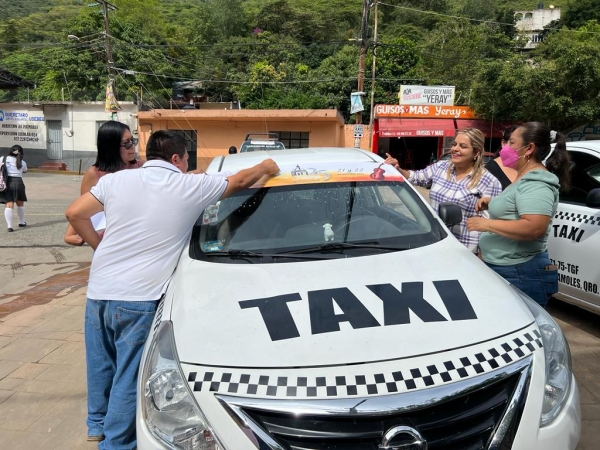 Coloca Lupita Ramírez calcomanías difundiendo el 25 Festival de Huapango en Ahuacatlán de Guadalupe.